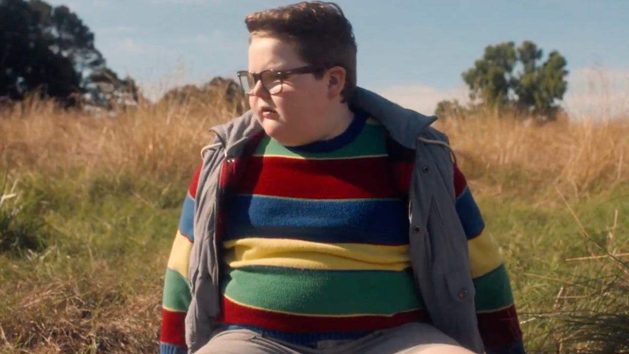 Jake Connelly as Derek Turnbow in Stranger Things. He is looking to his right, confused, sitting in a field.