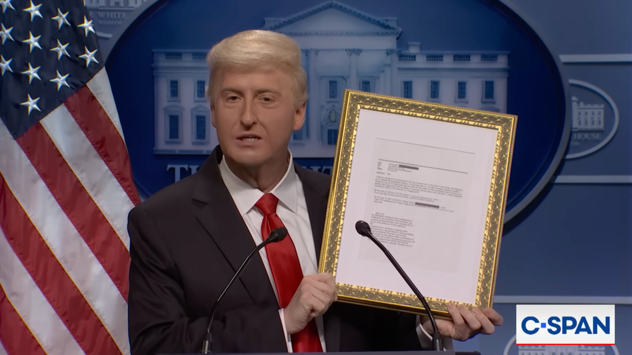 James Austin Johnson as Donald Trump speaking in front of a presidential lectern and holding up a gold-framed copy of an Epstein email.