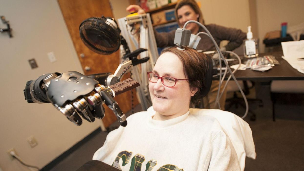 Jan Scheuermann, who has quadriplegia, brings a chocolate bar to her mouth using a robot arm she is guiding with her thoughts