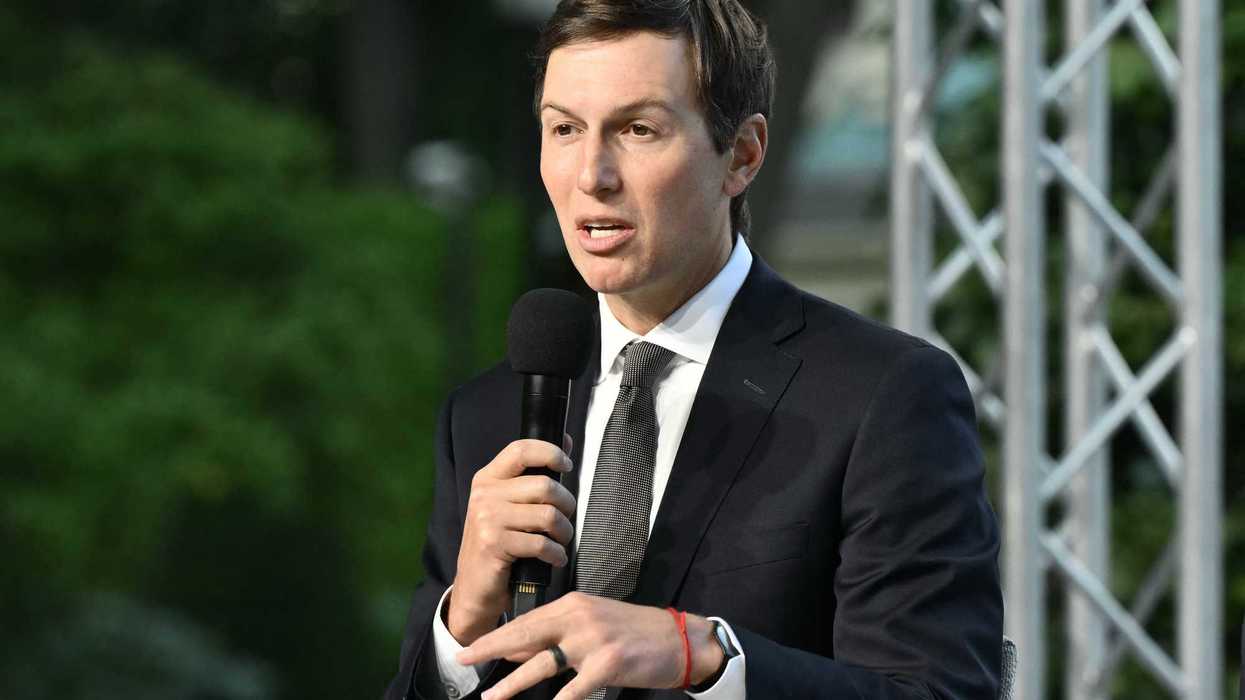 Jared Kushner, a white man with short black hair and a black suit, speaking into a microphone on-stage.