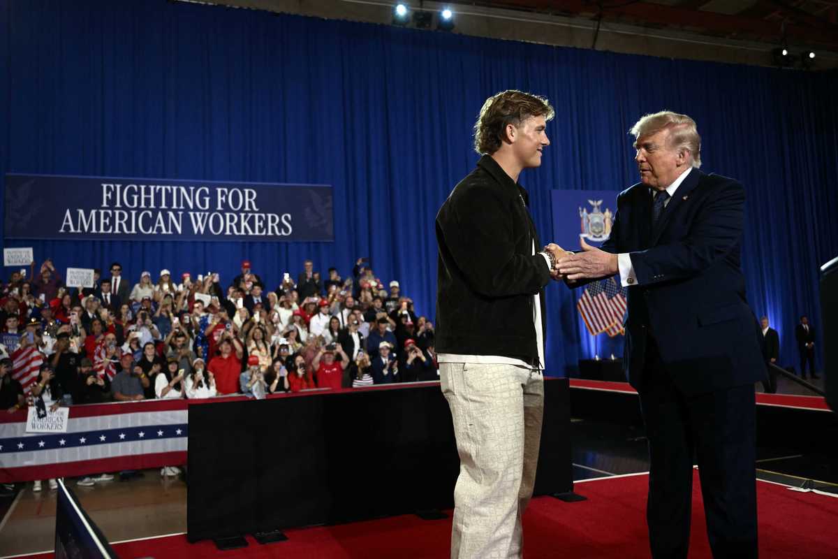 Jaxson Dart and Donald Trump shake hands on stage at a rally in New York.