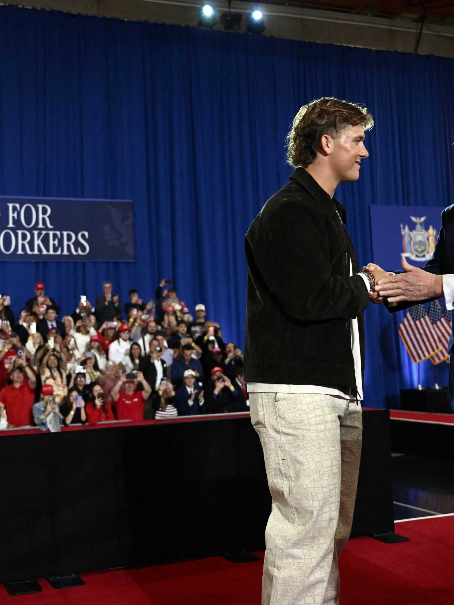 Jaxson Dart and Donald Trump shake hands on stage at a rally in New York.