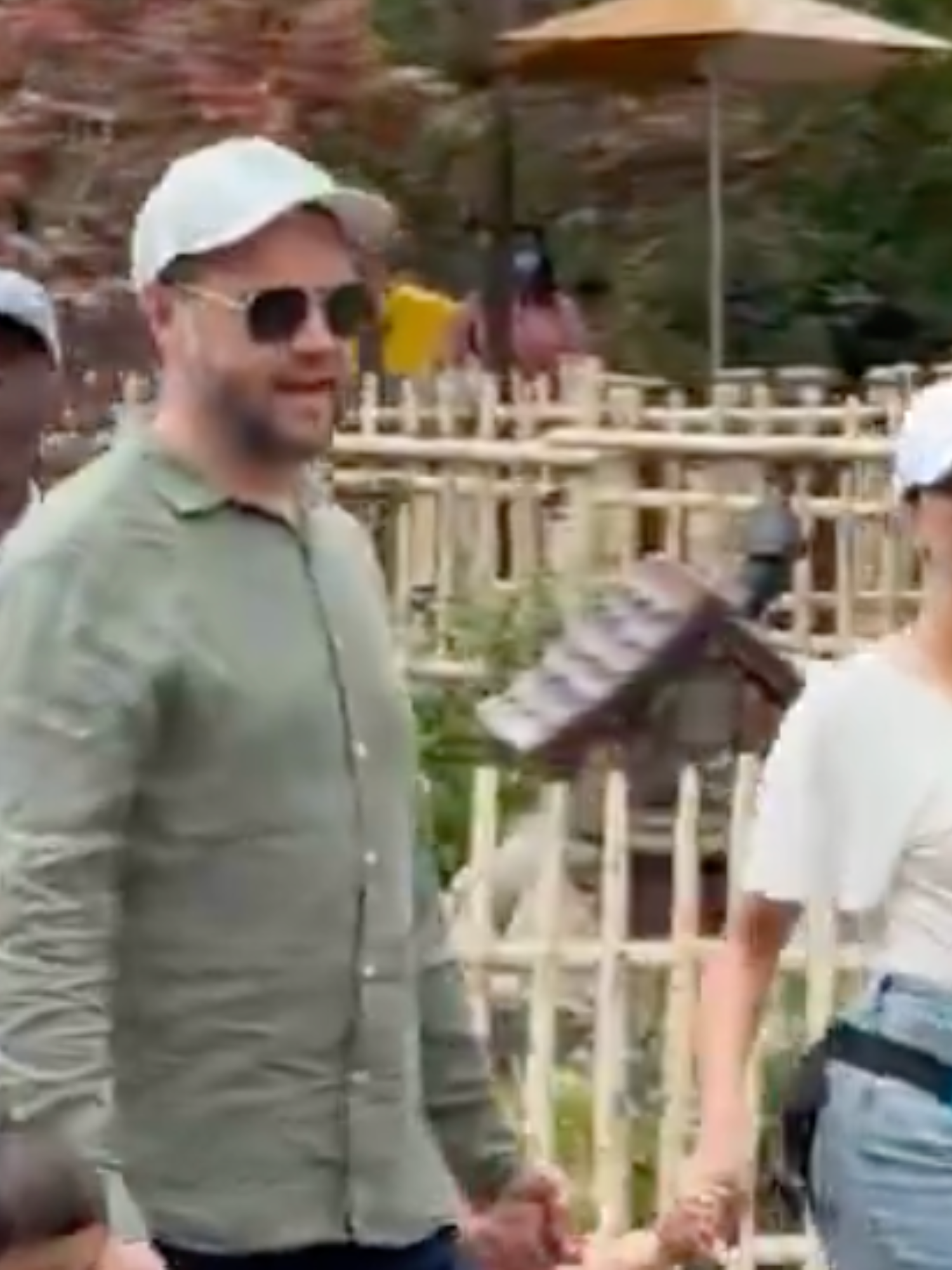 JD Vance in sunglasses and white cap walks through Disneyland with a group of people.