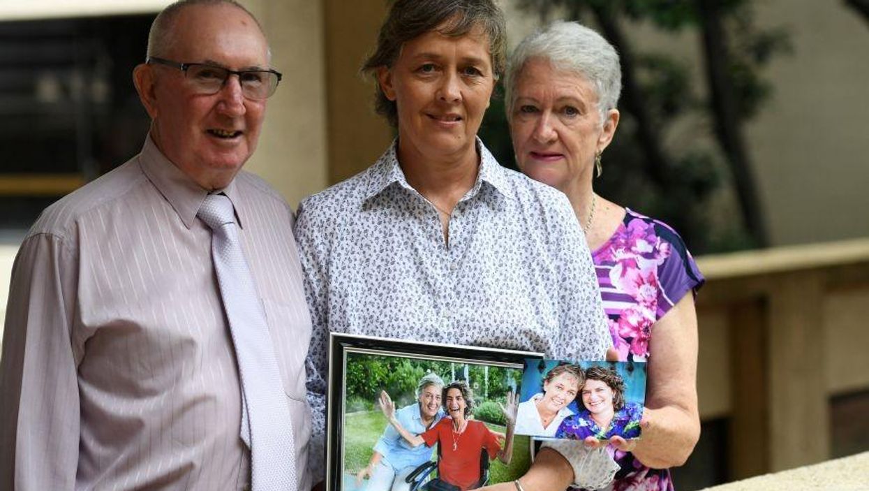 Jill Kindt holds a photo of her with her late wife Jo Grant, joined by Jo's mother Sandra Kelly and her husband Paul