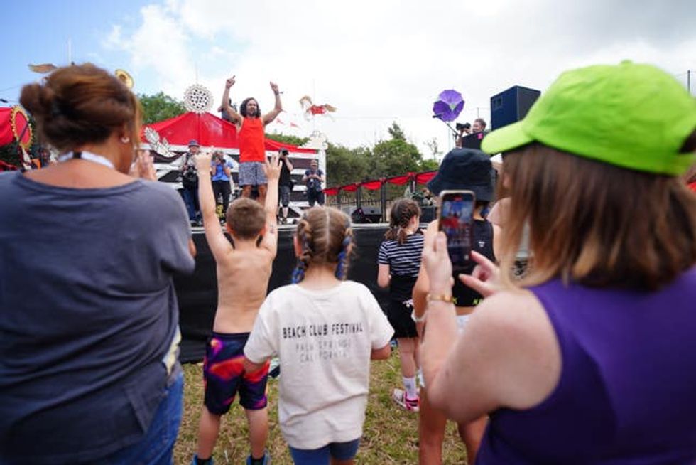 Joe Wicks raises his arms on stage in front of children and adults
