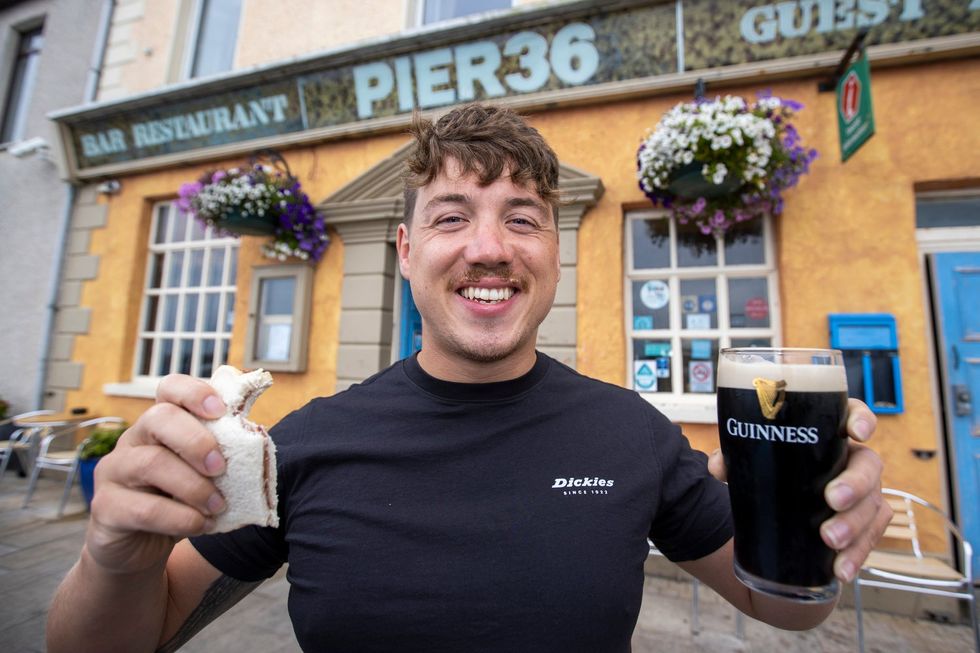 Jordan Leckey holding a celebrity jam sandwich and pint of Guinness outside Pier 36 at Donaghadee Harbour in Northern Ireland. Jordan set off on Monday swimming to Portpatrick in Scotland in the record time of nine hours and nine minutes. PA Photo. Picture date: Tuesday August 03 2021. See PA story ULSTER Swim. Photo credit should read: Liam McBurney/PA Wire