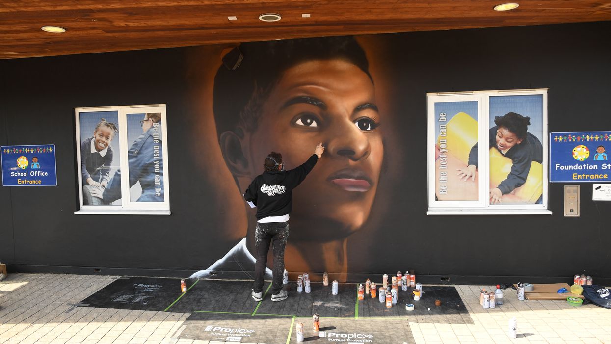 Josh from street artists MurWalls paints a mural of footballer Marcus Rashford on the wall of Gainsborough Primary School