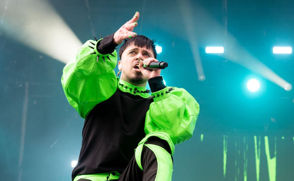 K\u00e4\u00e4rij\u00e4, a white man with short black hair and a neon green outfit, performs on stage.