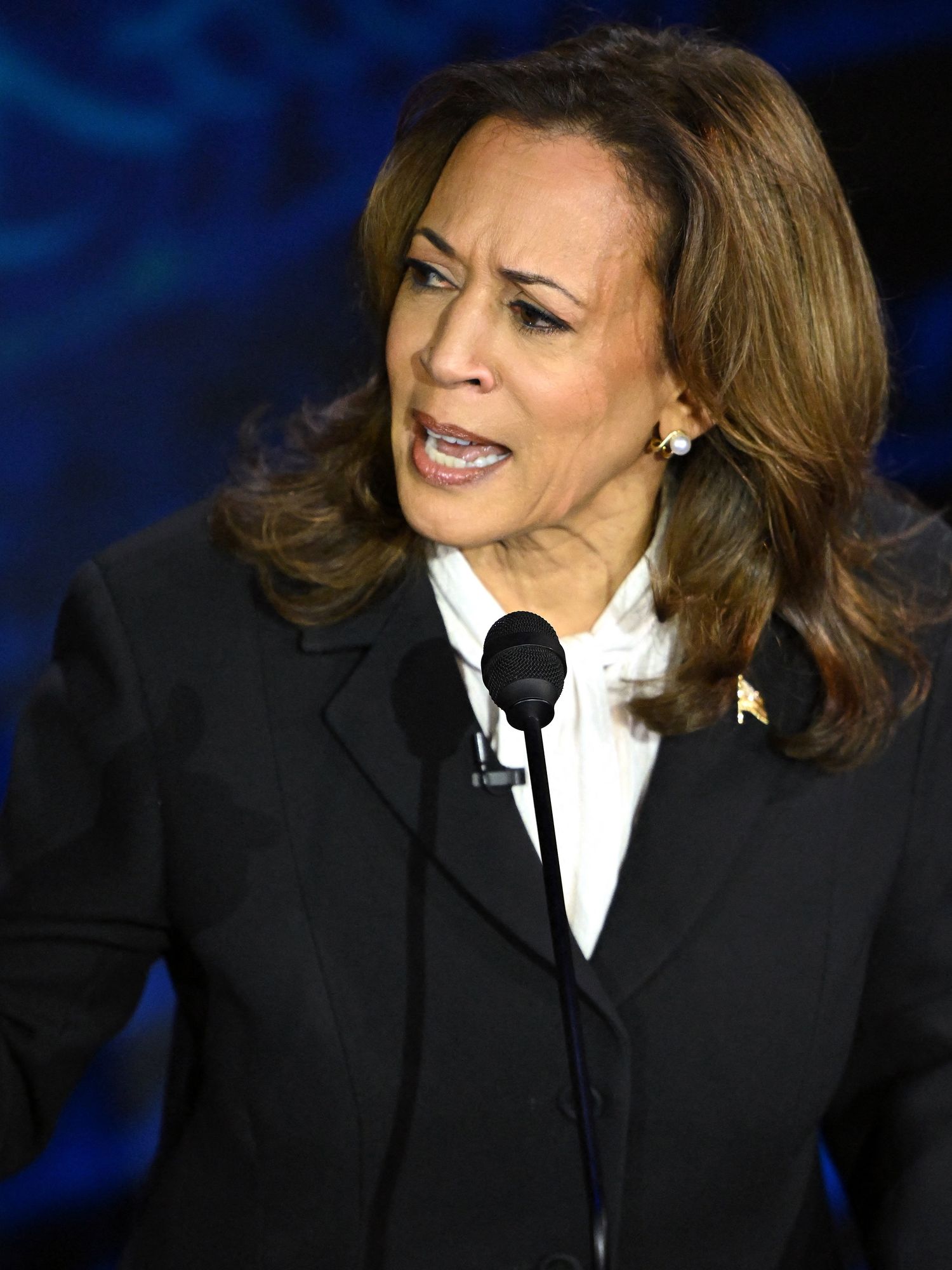 Kamala Harris points with her right hand at Trump off-camera during a presidential debate. She is wearing a black suit.