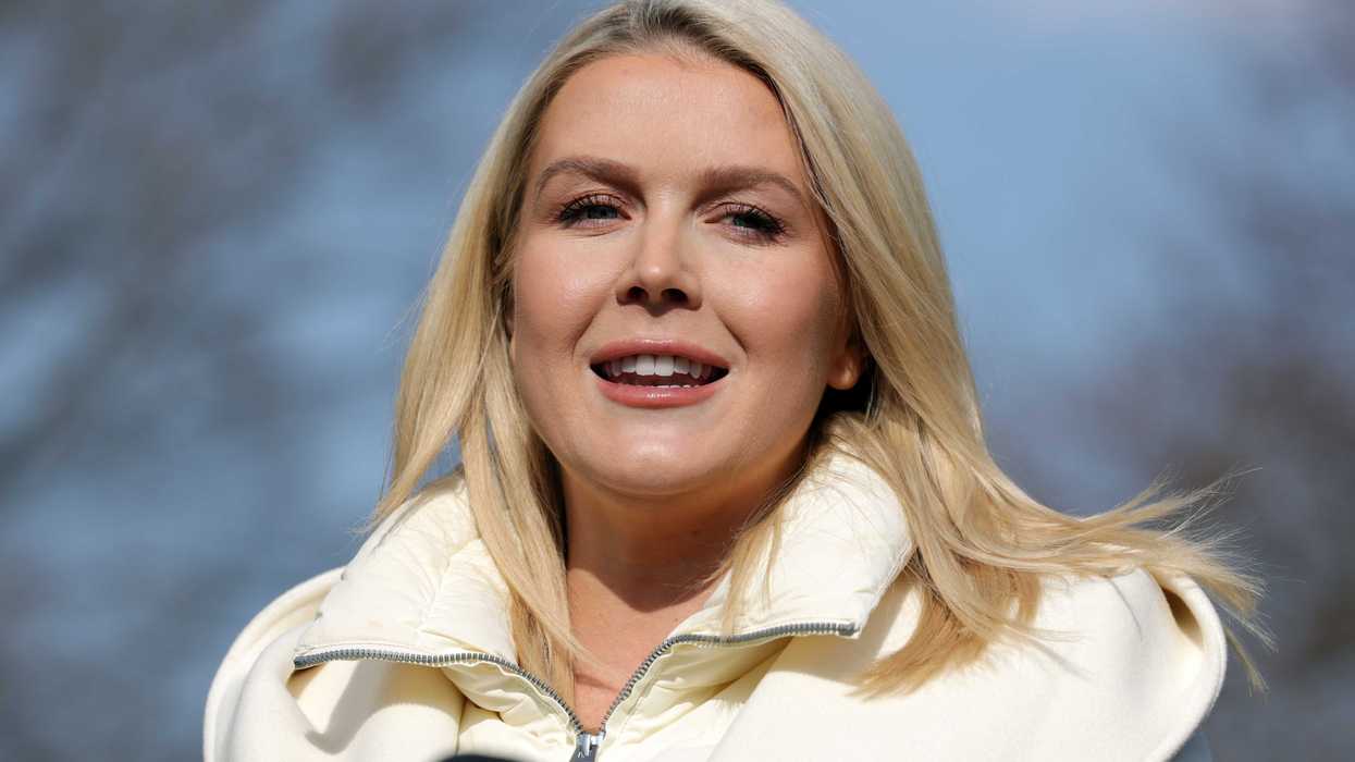 Karoline Leavitt, a white woman with long blonde hair and a white coat, standing outside the White House.