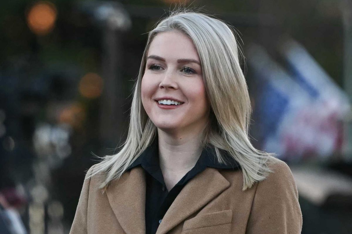 Karoline Leavitt, a white woman with short blonde hair and a brown coat, smiling.