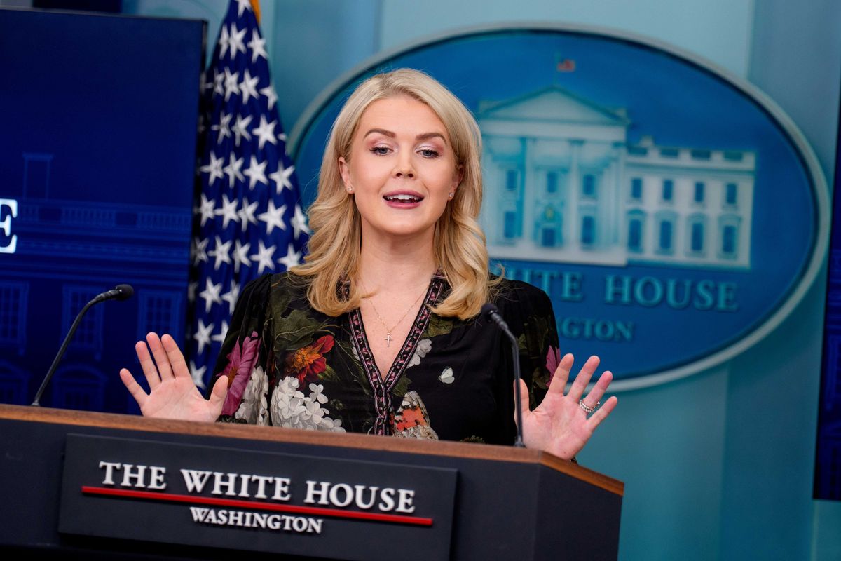 Karoline Leavitt speaks to press from a dark blue presidential lectern inside the White House.