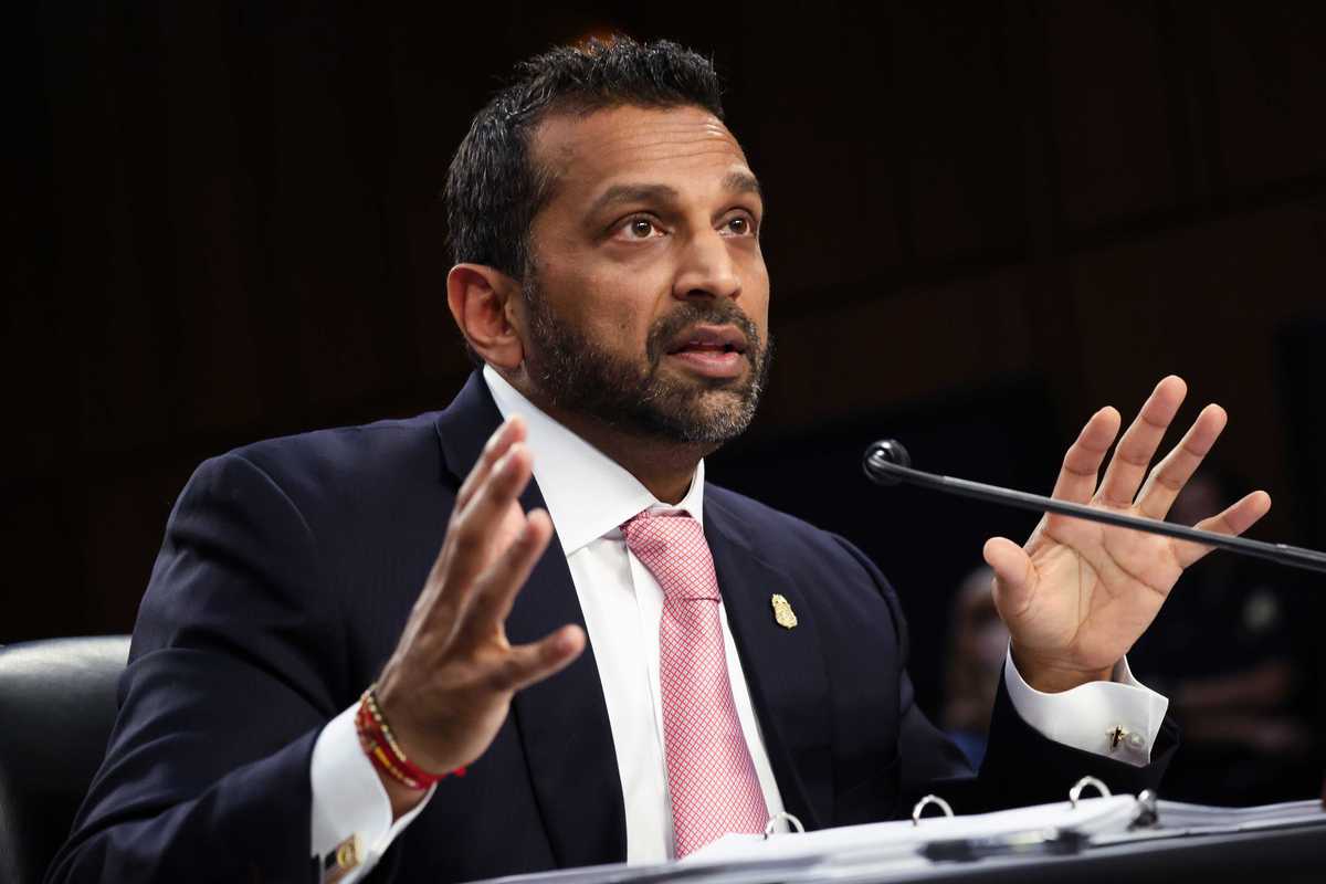 Kash Patel, a bearded brown man with short black hair and a dark blue suit, speaking at a Senate hearing.