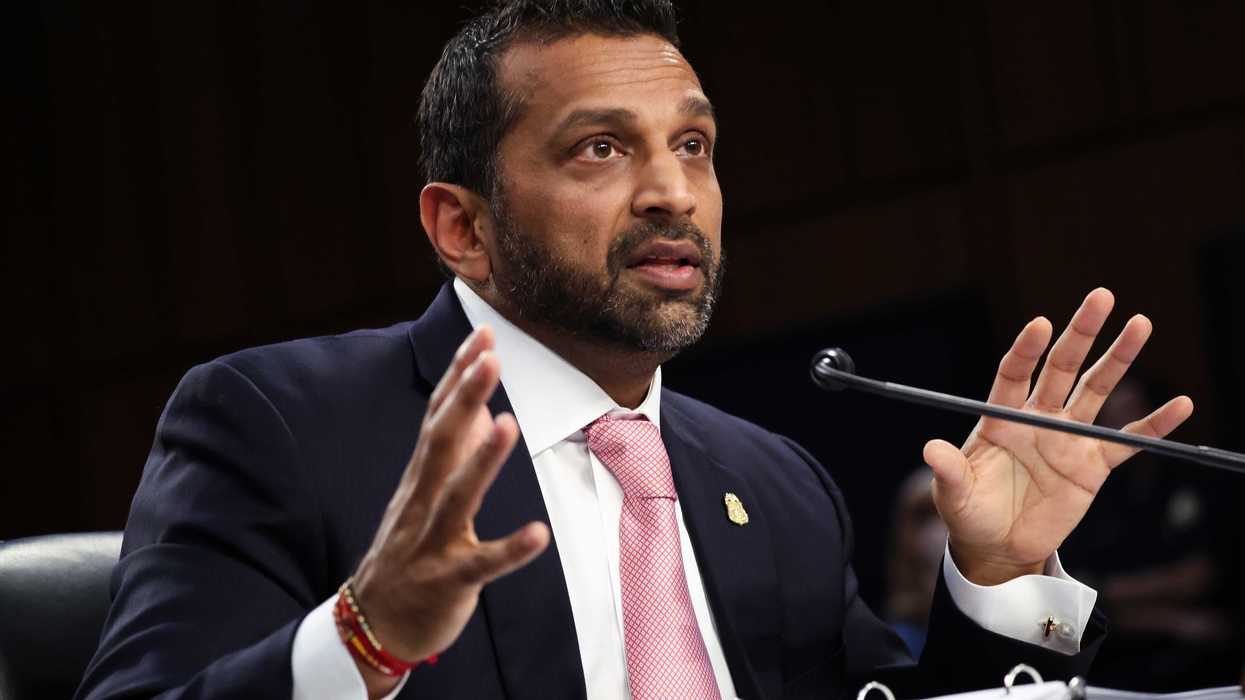 Kash Patel, a bearded brown man with short black hair and a dark blue suit, speaking at a Senate hearing.