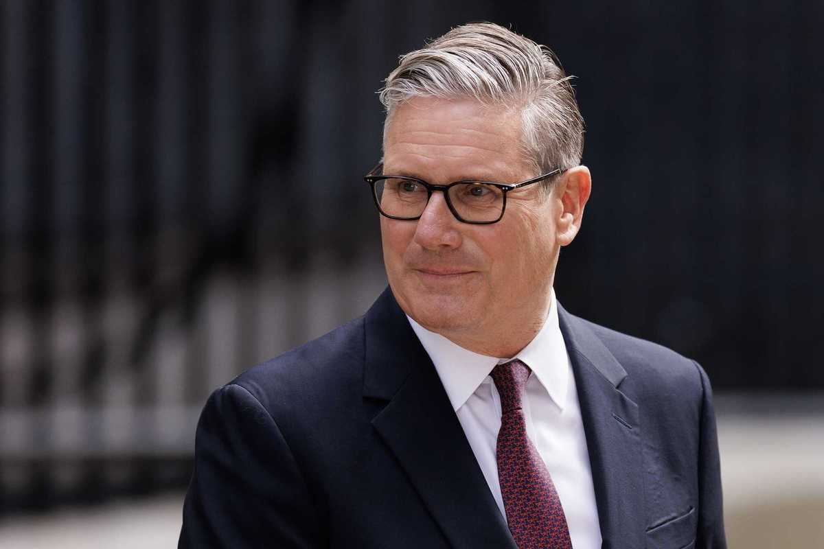 Keir Starmer looks to his right and smiles while standing outside Number 10.