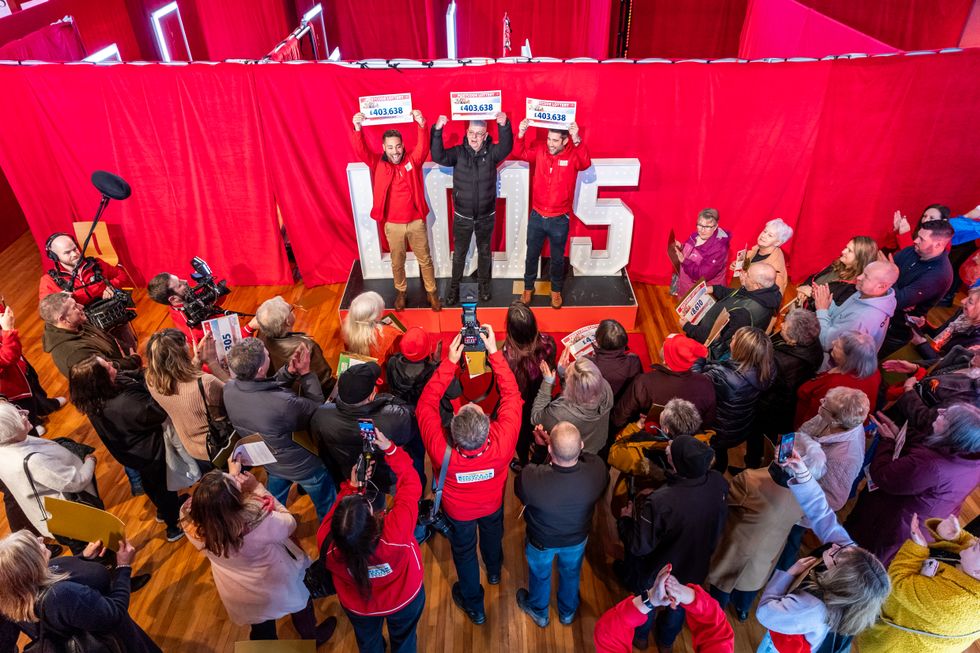 Kevin Jones standing on a podium holding up his tickets after receiving his jackpot win