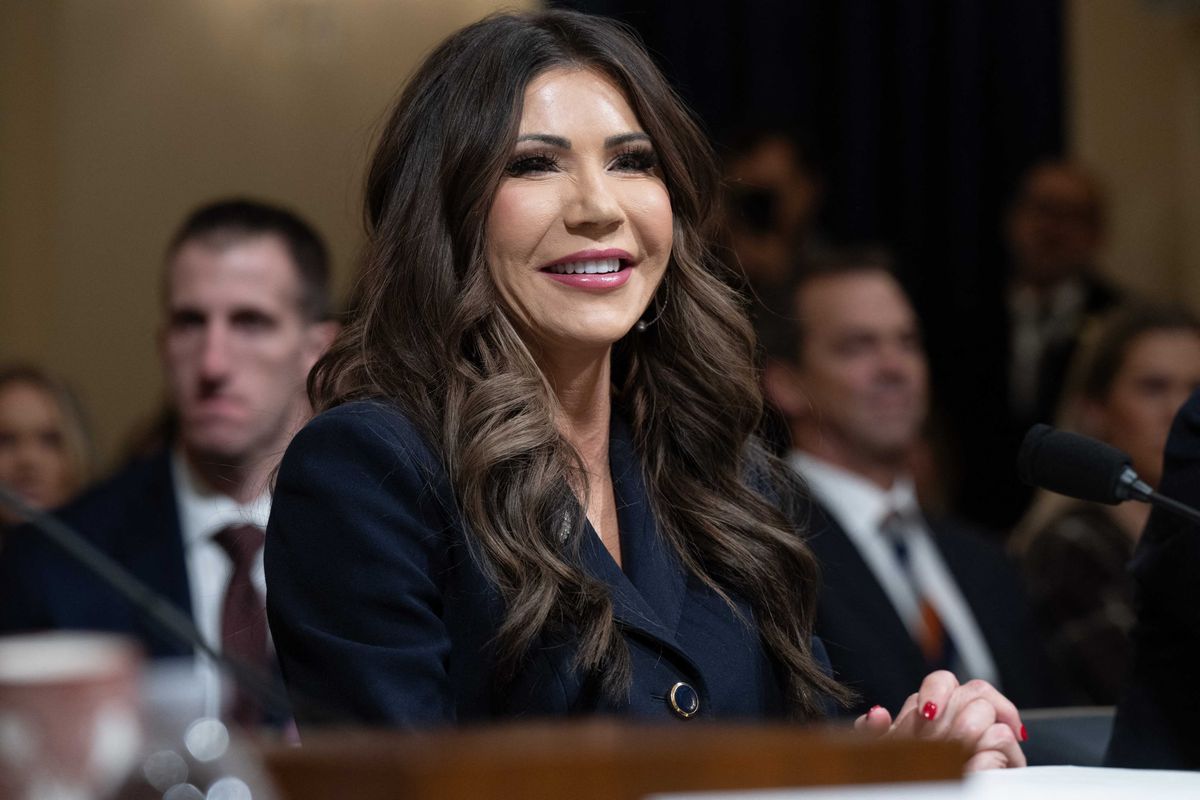 Kristi Noem, a white woman with wavy brown hair, smiles as she answers questions during a committee hearing.