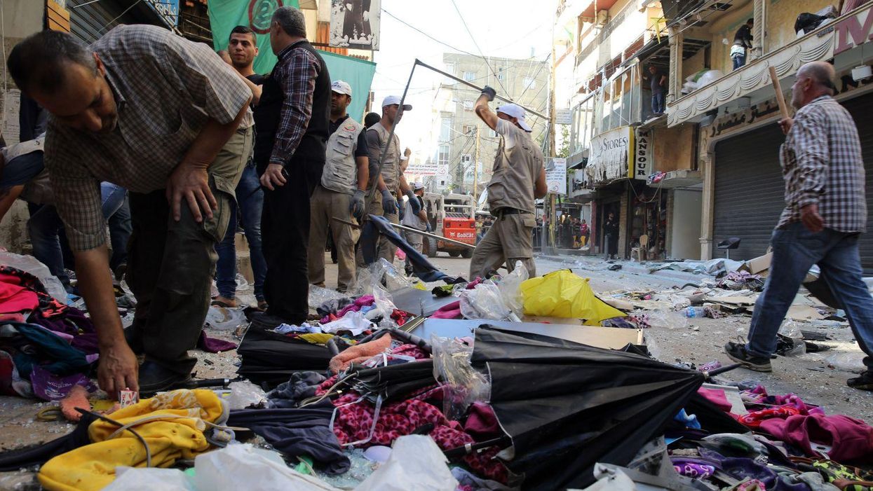 Lebanese municipality workers clear debris from the site of a twin bombing attack in Beirut's southern suburb on 13 November 2015