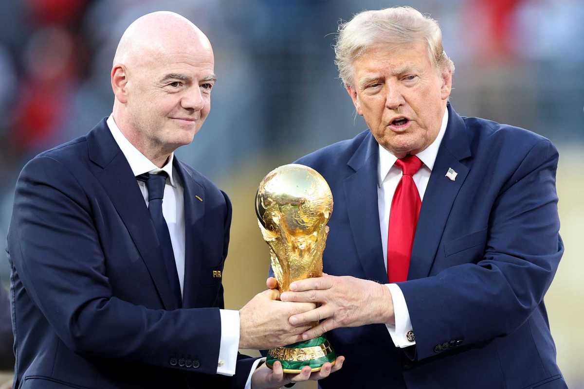 Left, Gianni Infantino and right, Donald Trump, both holding the golden World Cup trophy in the middle of them.