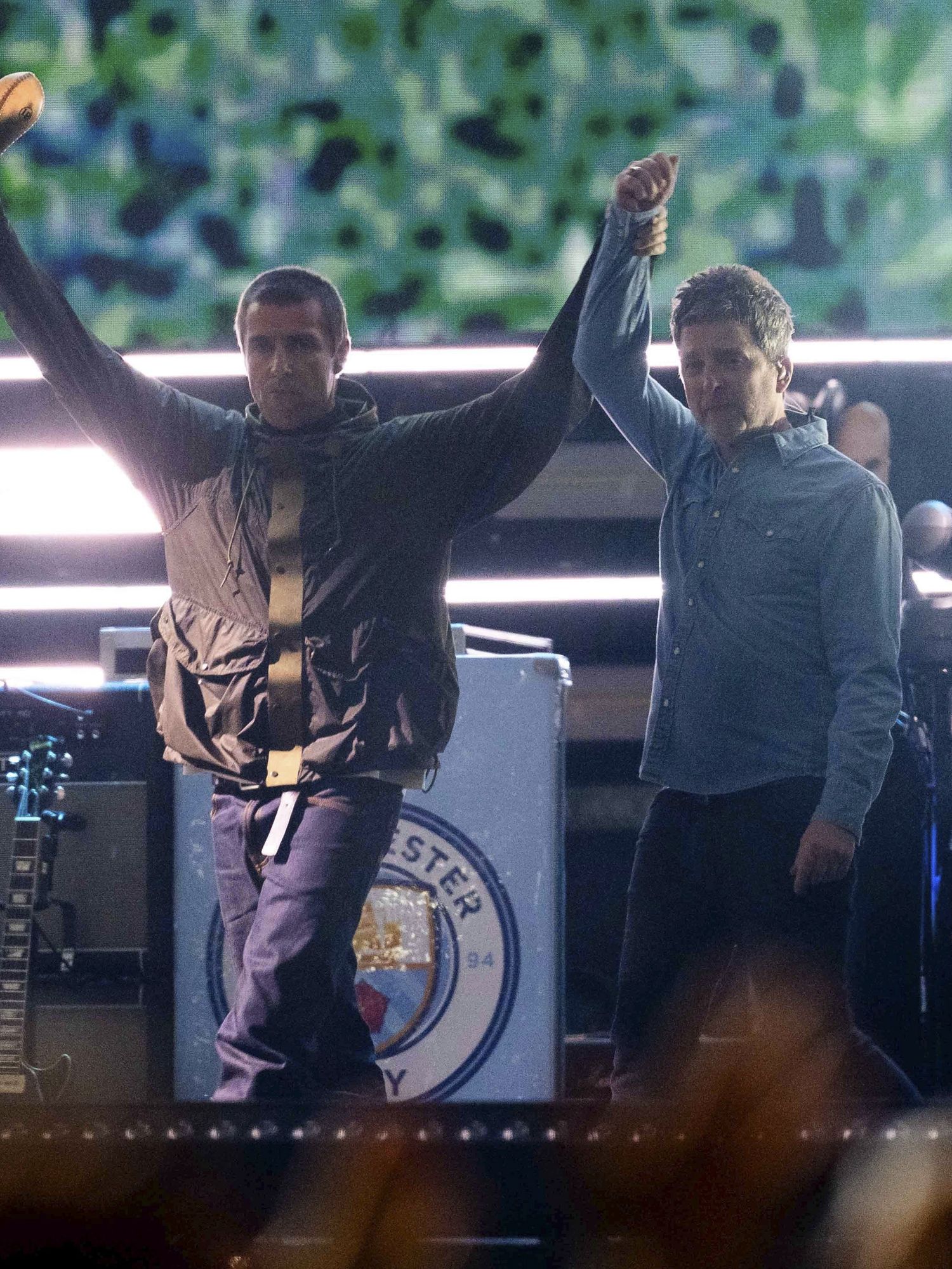 Liam Gallagher, left, holds the hand aloft of Noel Gallagher from the band Oasis as they perform during their reunion concert on Friday, July 4, 2025, in Cardiff