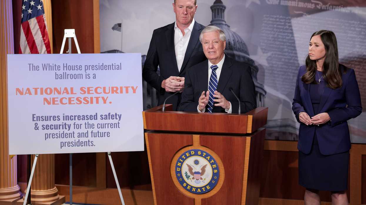 Lindsey Graham, a white man with short grey hair, speaks behind a wooden lectern. A white man and white woman stand behind him. A canvas on his right displays the text: 'The White House presidential ballroom is a national security necessity. Ensures increased safety & security for the current president and future presidents.'