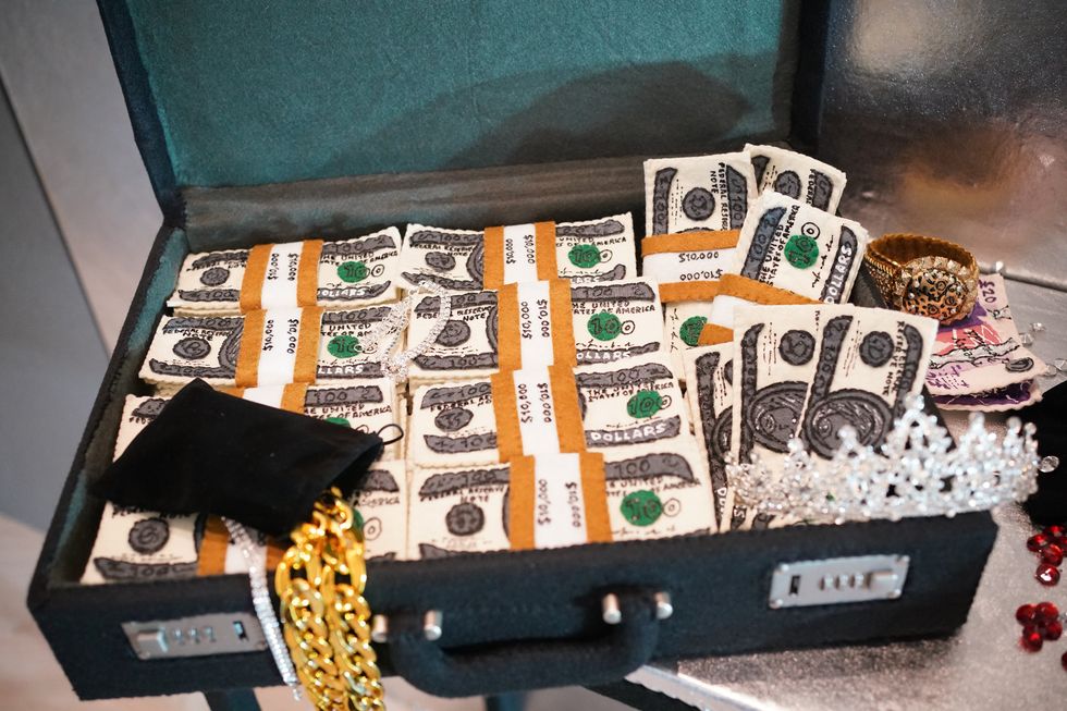 Lit by the headlights of the police car, we see the contents of the bank vault, including millions of dollars in cash, passports and jewellery (Yui Mok/PA)