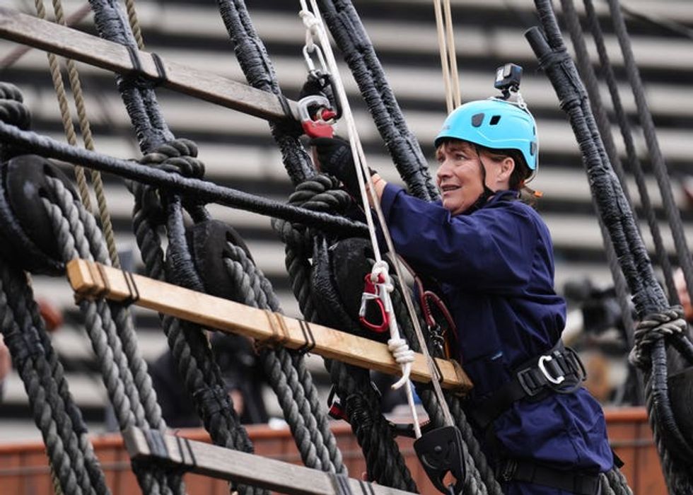 Lorraine Kelly in hard hat and boiler suit climbing the rigging of a ship