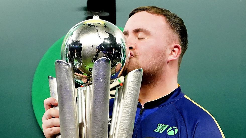 Luke Littler kisses the WDC trophy