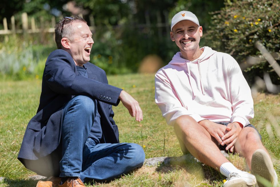 Luke Melling and Alastair Hawken sitting next to each other in a park