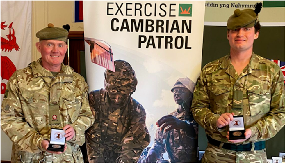 Major David 'Harry' Hood alongside his son Corporal Declan Hood dressed in military fatigues and holding their medals