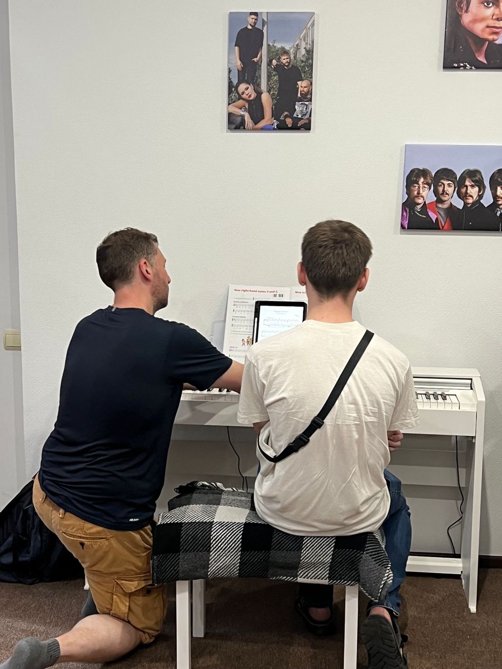 Man helping boy play the piano