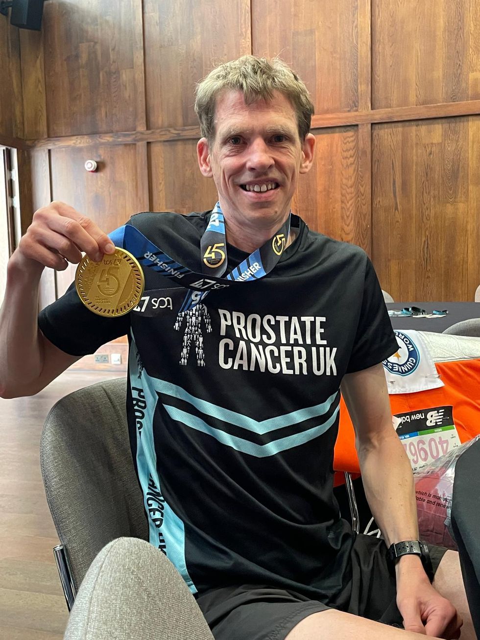 Man sitting and holding medal to camera