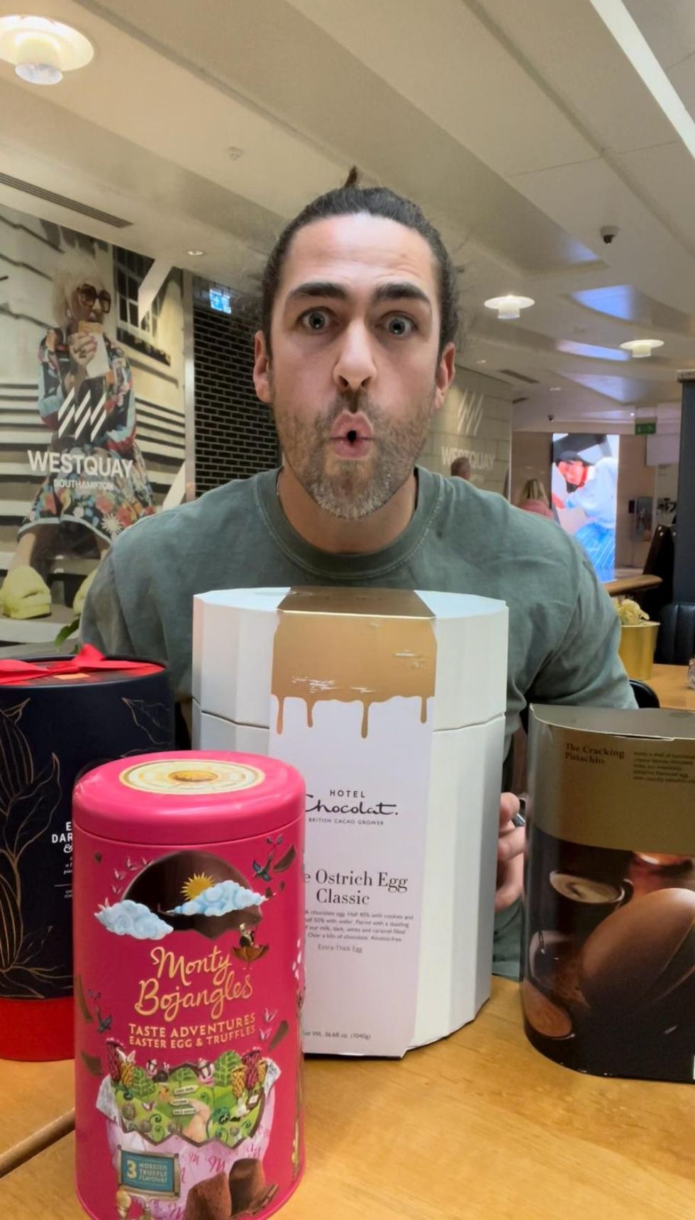 Man sitting behind a range of Easter egg boxes making a shocked face