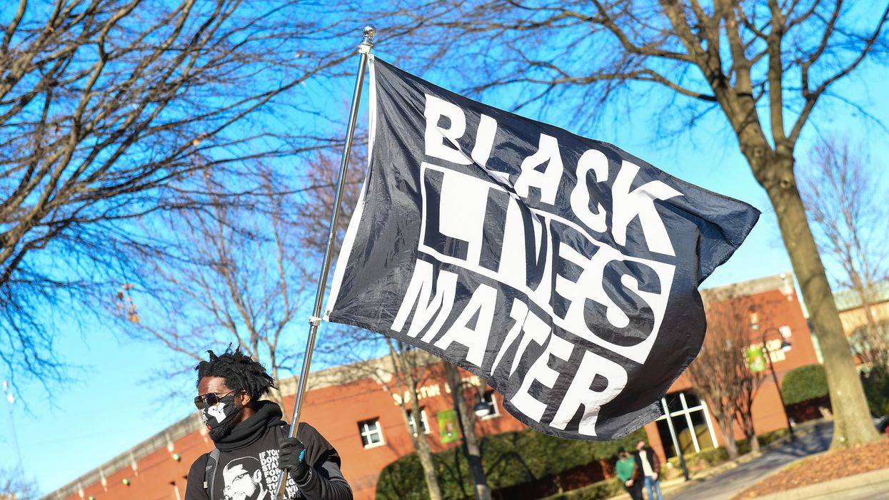 <p>Man waves Black Lives Matter flag</p>