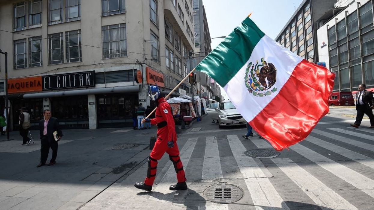 <p>Man waves Mexican flag.</p>