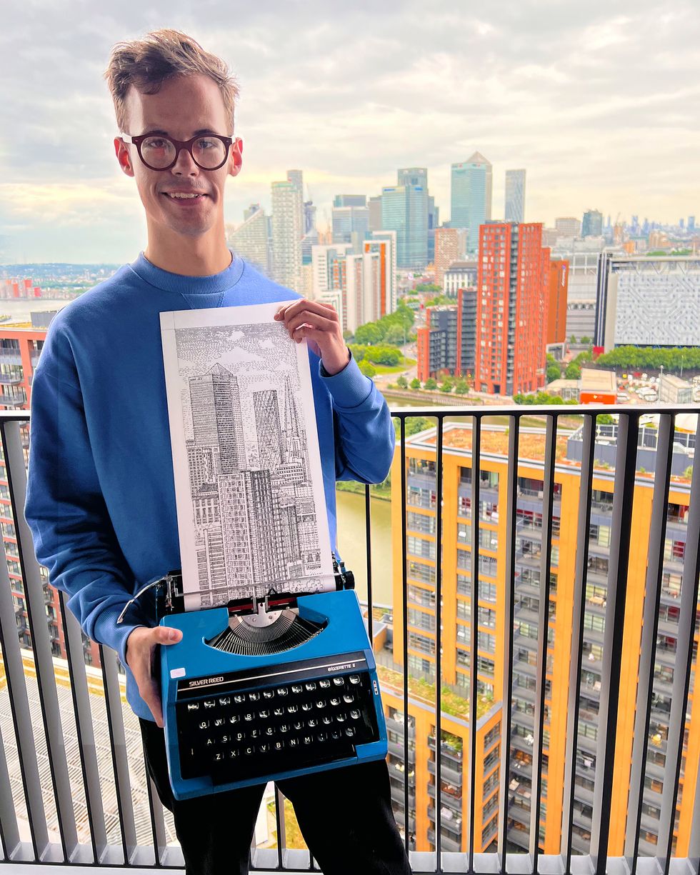 Man wearing a blue hoodie and holding a piece of art made with a typewriter