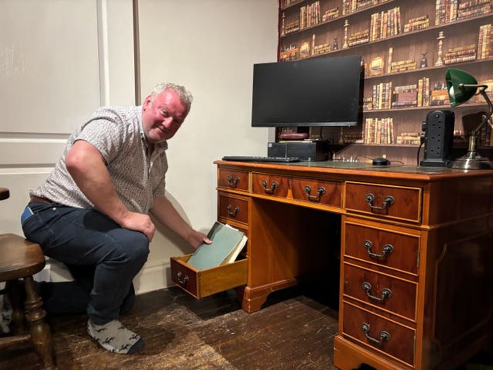 Martin Reid holding folders as he takes them out of the bottom drawer of a wooden desk