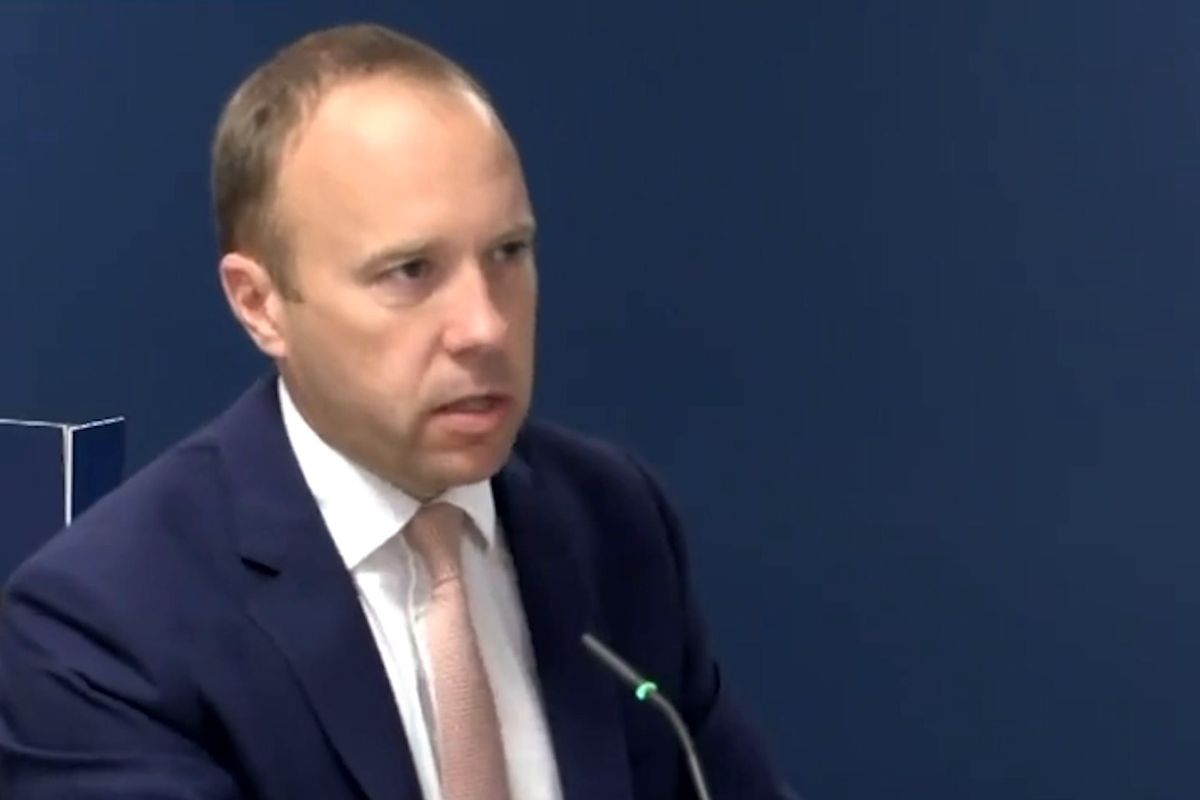 Matt Hancock, a white man with a large forehead, short black hair and a blue suit, sits in a chair in front of a microphone giving evidence to an inquiry.