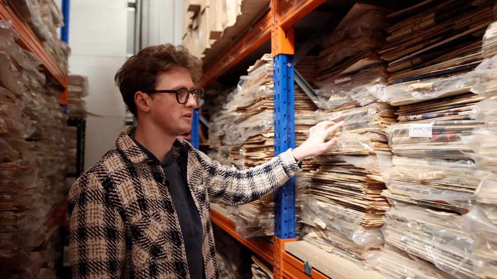 Max Fosh looking through piles of newspapers