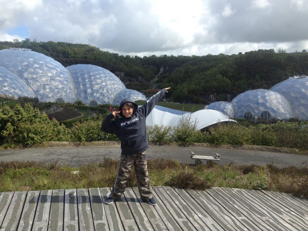 Max Schiller, who died in 2015, holds a Usain Bolt pose. He is wearing a black hoody and camouflage trousers, standing on wooden decking, with greenhouses and trees in the background against a grey sky