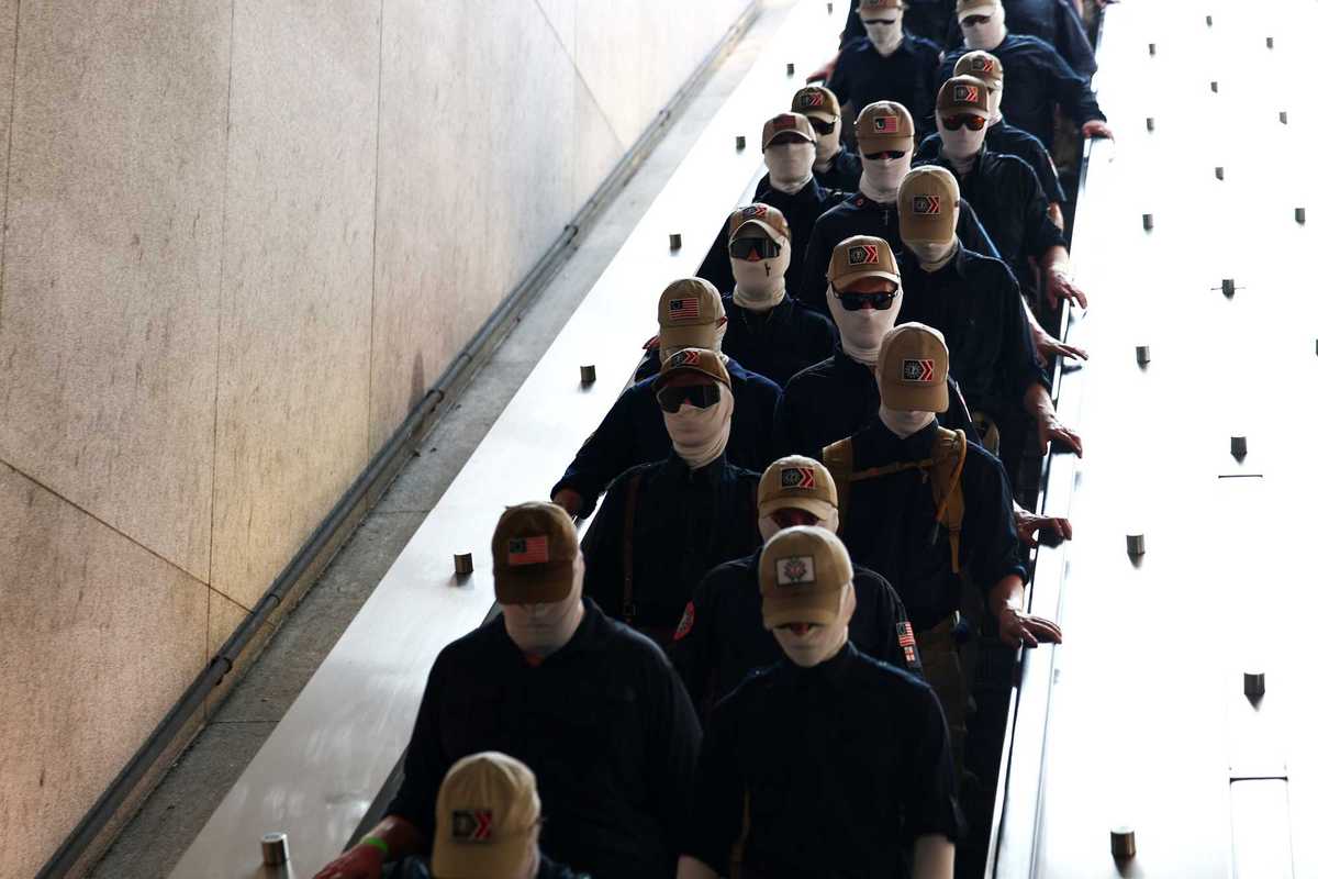 Members of Patriot Front in beige caps and balaclavas board the metro in Washington, D.C.