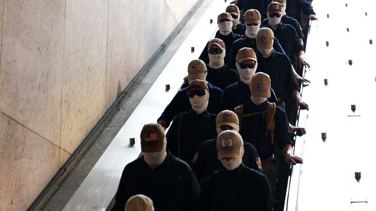 Members of Patriot Front in beige caps and balaclavas board the metro in Washington, D.C.