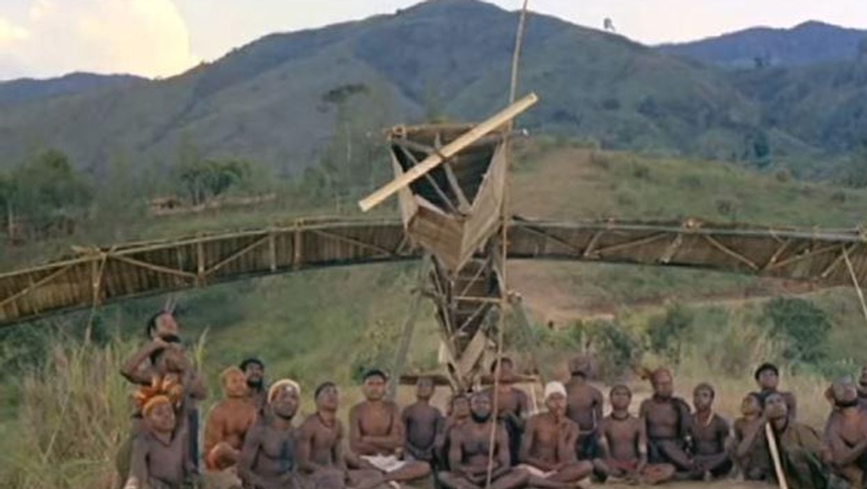 Members of the cargo sect sitting next to a replica they built.
