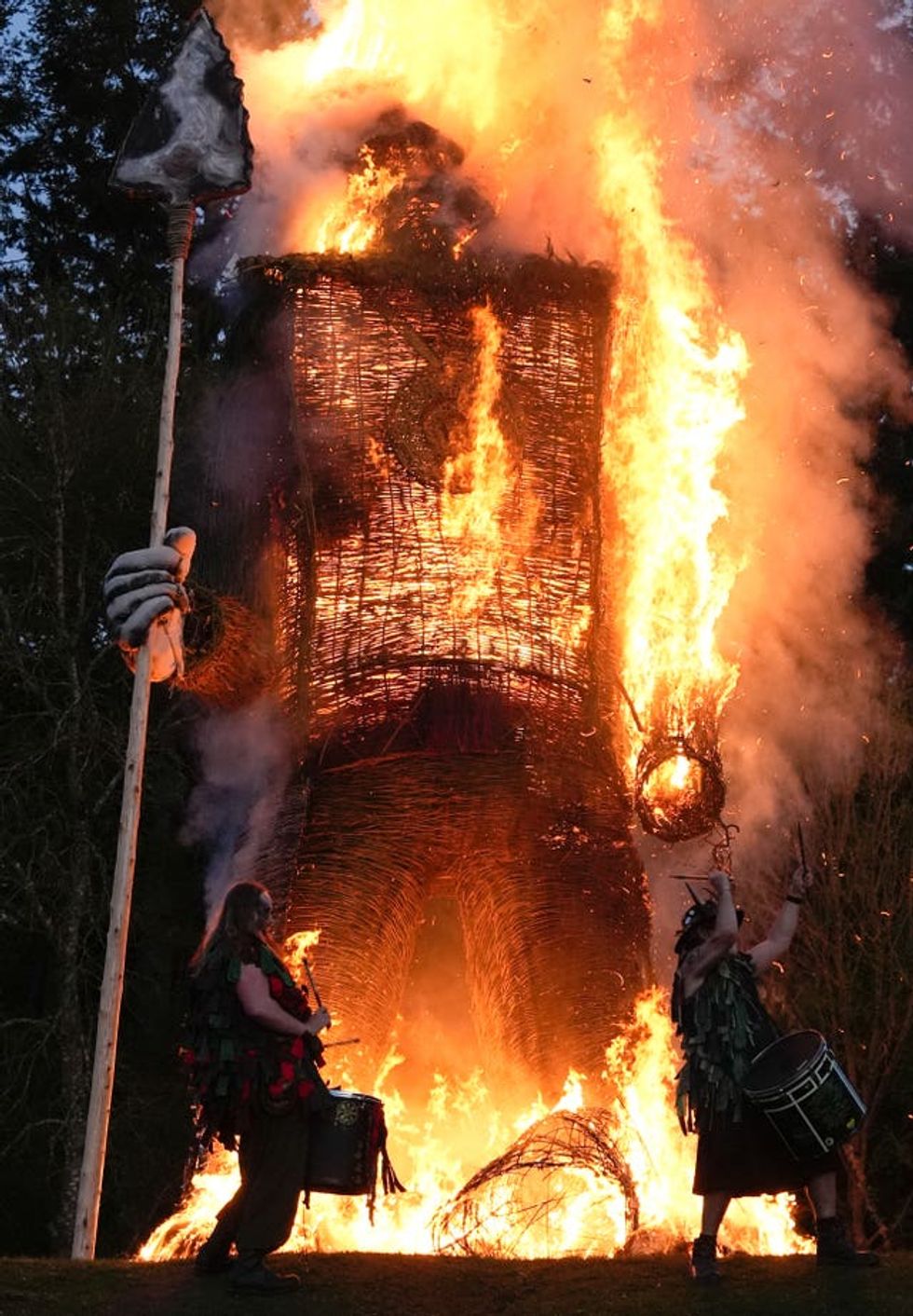 Members of the Pentacle Drummers perform in front of a burning wicker man during the Beltain Celtic Fire Festival at Butser Ancient Farm, near Waterlooville, Hampshire