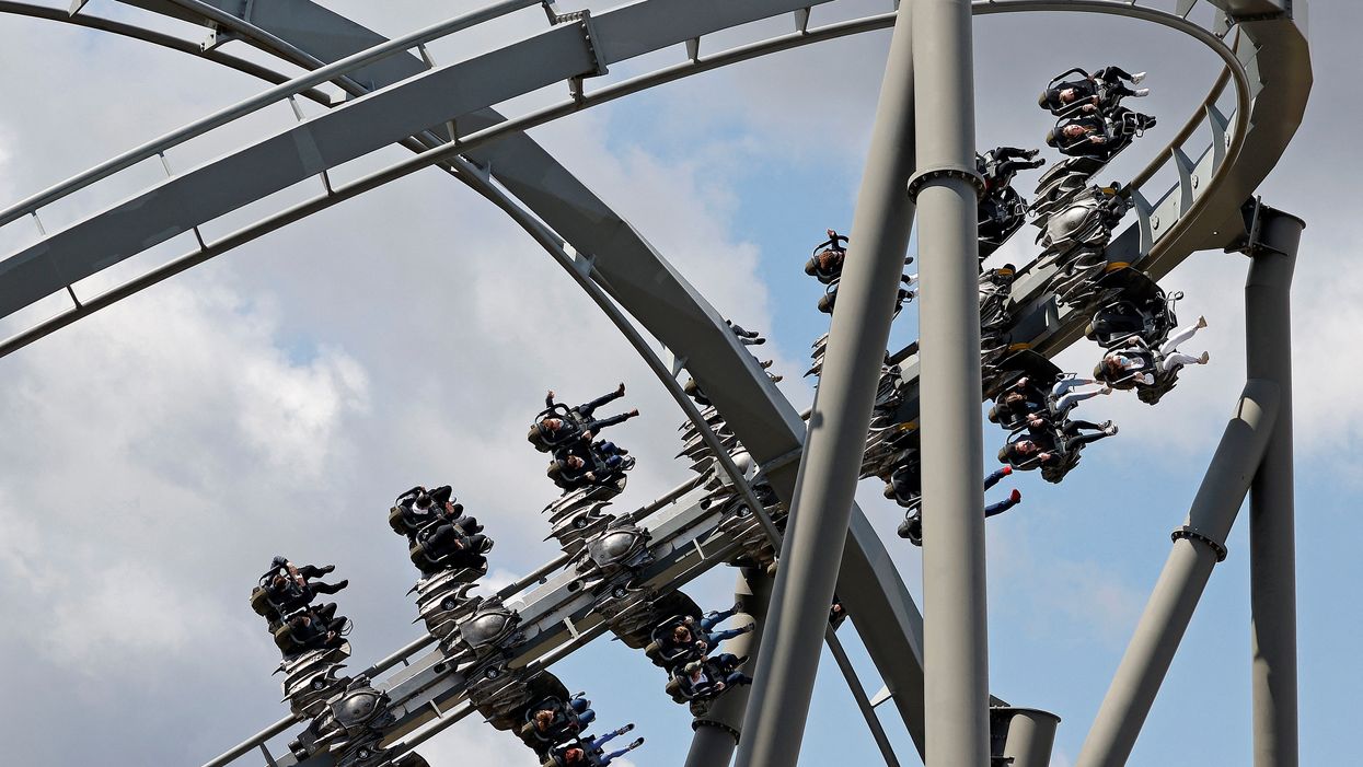 Members of the public enjoy the Swarm rollercoaster ride - a silver coaster with the track at the top - at Thorpe Park.