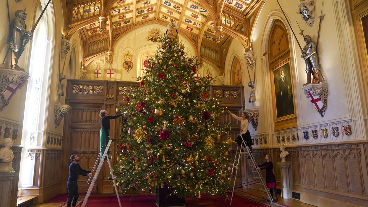 Members of the Royal Collection Trust staff put the finishing touches to a Christmas tree in St George’s Hall (Steve Parsons/PA)