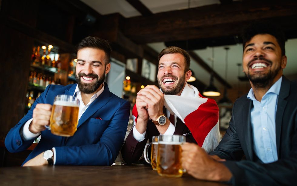 Men watching football in the pub while drinking beer.