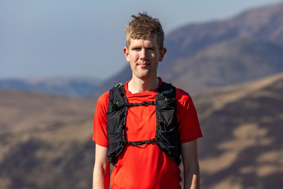 Mid close-up picture of adventurer Alex Staniforth standing for a picture with mountainous terrain in the background