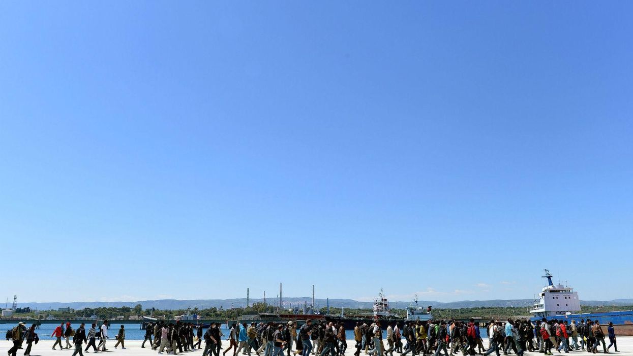 Migrants disembark an Italian naval ship in the Sicilian port of Augusta on 22 April