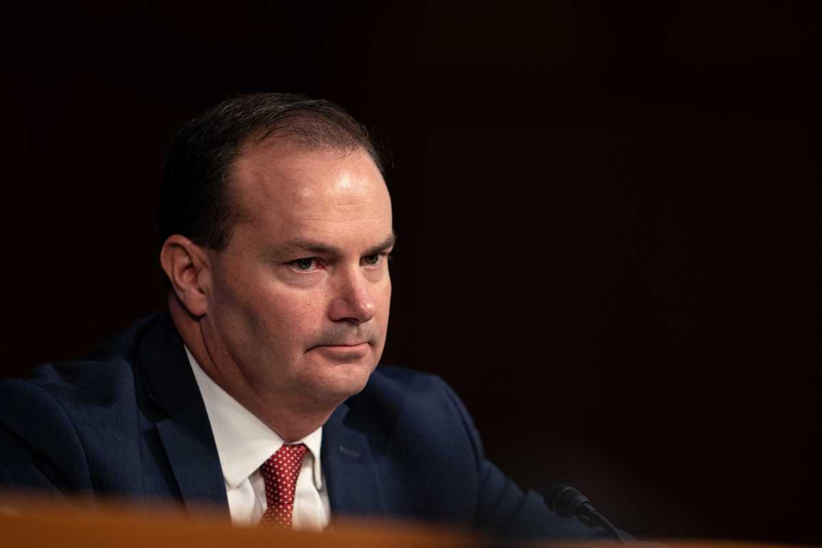 Mike Lee, a white ma n with short black hair and a blue suit, sitting at a congressional hearing.